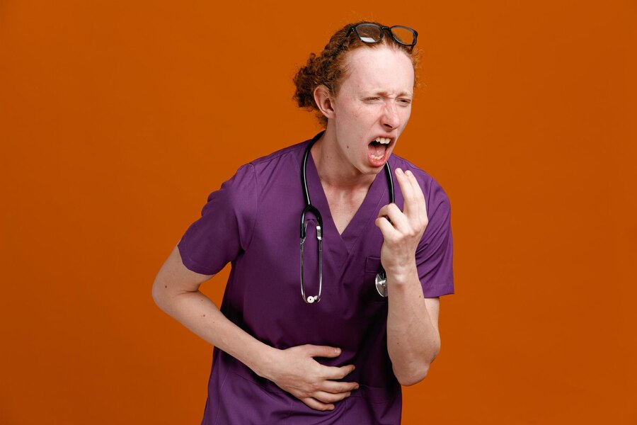 Caughing grabbed stomach young male doctor wearing uniform with stethoscope isolated on orange background