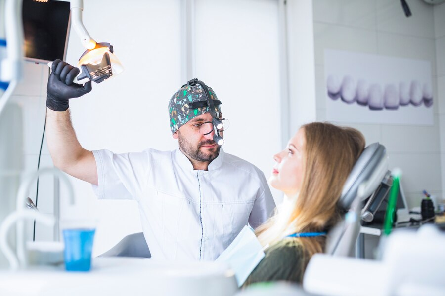 Dentist wearing dental loupe binoculars treating female patient