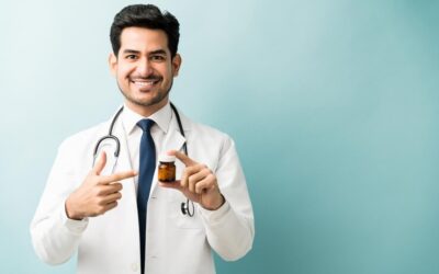 Smiling handsome doctor showing medicine bottle against blue background